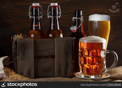 Beer glass and crate with beer bottles on burlap cloth with barley seeds
