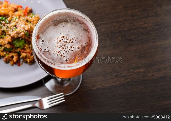 Beer glass and food on black table with food, view from above.