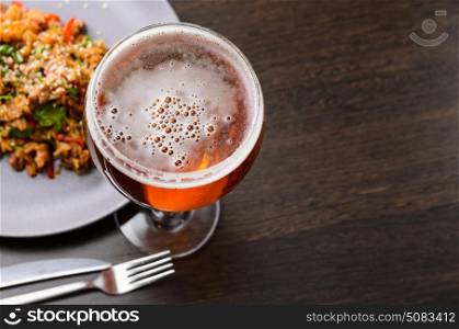 Beer glass and food on black table with food, view from above.