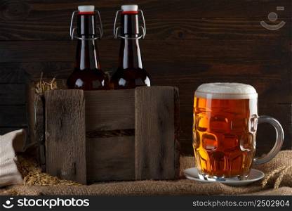 Beer glass with beer bottles in wooden crate on burlap cloth