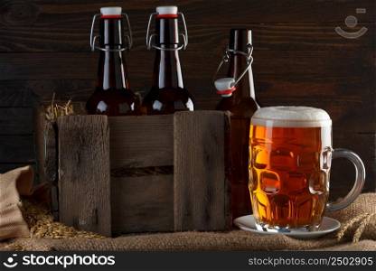 Beer glass with beer bottles in wooden crate on burlap cloth