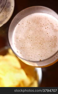 Beer glass with some snacks in the background