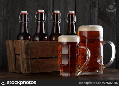 Beer glass with vintage wooden box full of beeer bottles on wooden table still life