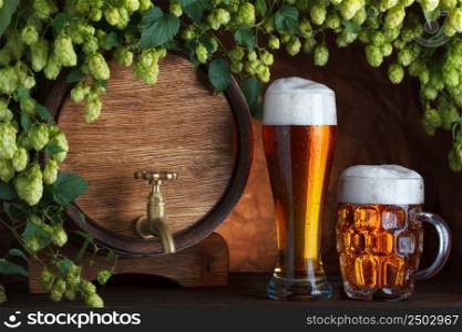 Beer glasses and beer barrel with fresh hops cones still-life