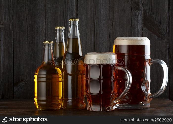 Beer glasses and bottles with variety of beer on wooden table still life