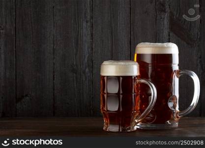 Beer glasses on table, dark wooden background with copy space