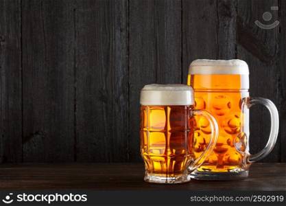 Beer glasses on table with burlap cloth, dark wooden background with copy space