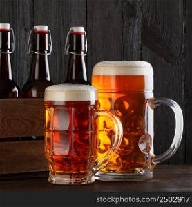 Beer glasses on table with crate, dark wooden background
