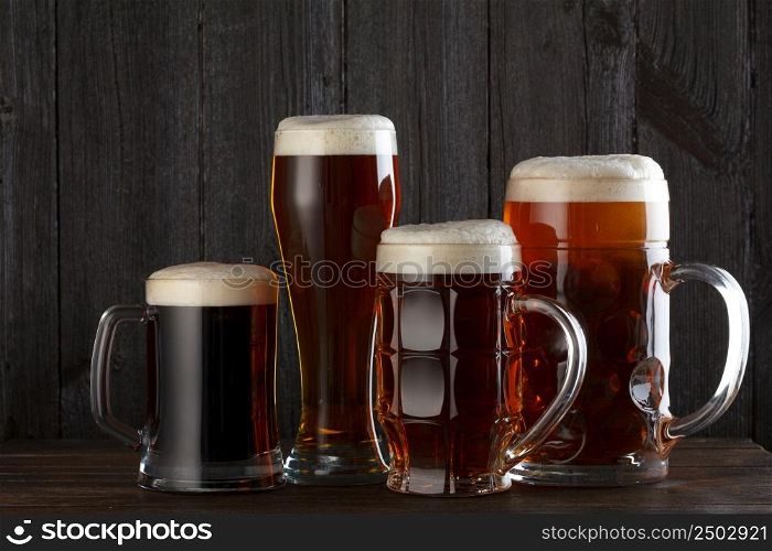 Beer glasses with lager, dark lager, ale, stout beer on table, dark wooden background