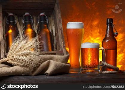 Beer glasses with wooden crate full of beer bottles and wheat ears on table