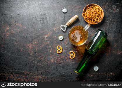 Beer in a bottle and a glass of snacks in the bowl. On rustic background. Beer in a bottle and a glass of snacks in the bowl.