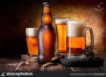 Beer in glass and bottle on wooden background. Light beer composition