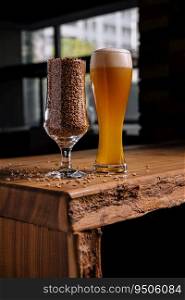 Beer in glass and wheat in glass on wooden table. glass of beer and wheat in glass on wooden table