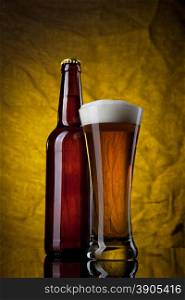 Beer in glass with bottle on yellow background