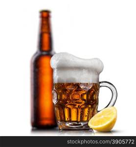 Beer in glass with water drops and lemon against bottle isolated on white