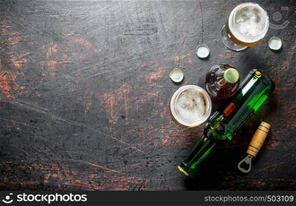Beer in glasses and bottles with opener and covers. On rustic background. Beer in glasses and bottles with opener and covers.