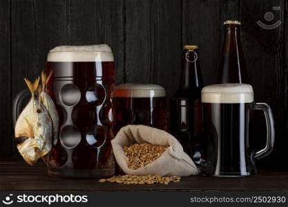 Beer mugs and bottles with smoked salty fish snack and bag of barley
