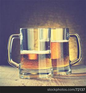 Beer mugs on the wooden table. Retro style filtred