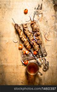 Beer with pork Shish kebab and tomatoes. On a wooden table.. Beer with pork Shish kebab and tomatoes.