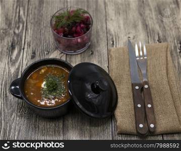 Beet salad and tomato, red pepper soup, sauce with olive oil, rosemary and smoked paprika with fork and knife on a wooden background.