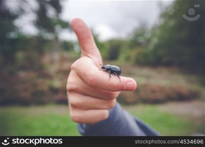 Beetle on a hand giving thumbs up in the nature