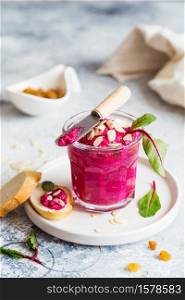 Beetroot dipping sauce in the glass decorated with almond petals and mangold leaves. Vegan recipes, plant-based dishes. Green living concept