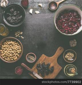 Beetroot salad preparation with vegan  ingredients: beetroot, chickpeas, dates, garlic and pine nuts on dark grey kitchen table. Making healthy vegan friendly food at home. Top view. Frame