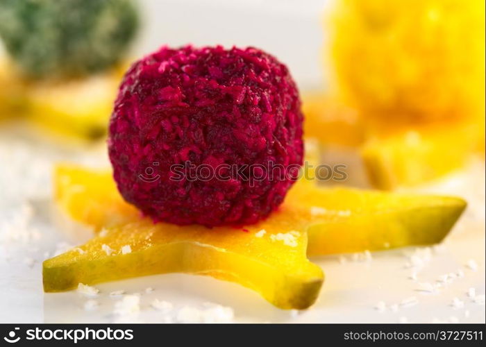 Beetroot, spinach and pumpkin coconut balls on a star fruit slice (Selective Focus, Focus on the front of the beetroot coconut ball). Vegetable Coconut Balls