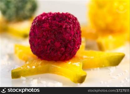 Beetroot, spinach and pumpkin coconut balls on a star fruit slice (Selective Focus, Focus on the front of the beetroot coconut ball). Vegetable Coconut Balls