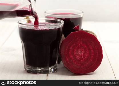 Beetroot with beet juice on white wood