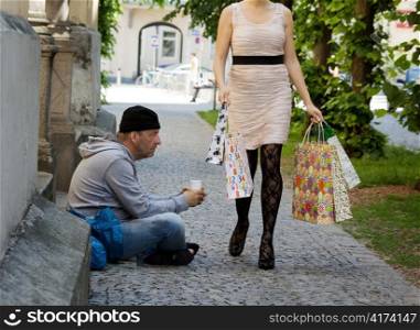 beggar and a rich young woman with shopping bags