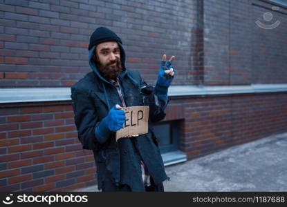 Beggar man and help sign on city street. Poverty is a social problem, homelessness and loneliness, alcoholism and drunk addiction. Beggar man and help sign on city street