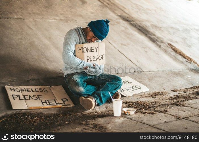 Beggars sitting under the bridge with a sign, please money.