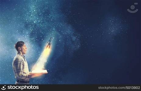 Behind imagination limits. Young shocked man with glowing book in hands and hero flying out of pages