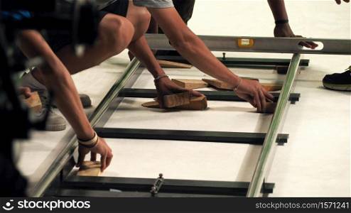 Behind the scenes of production team setting dolly track for camera equipment and video shooting in a big studio.