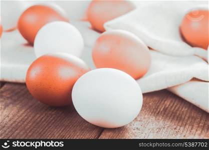 Beige and white chicken eggs on textile tablecloth over rustic wooden table