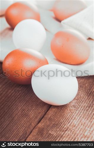 Beige and white chicken eggs on textile tablecloth over rustic wooden table