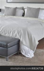 Beige blanket on comfy bed with black leather ottoman