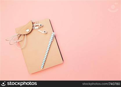 Beige diary with blue pen and headphones on pastel millennial pink paper background. Concept of education, blogging. Top view. Flat lay. Minimal style. Template for female blog. Lifestyle. Copy space.