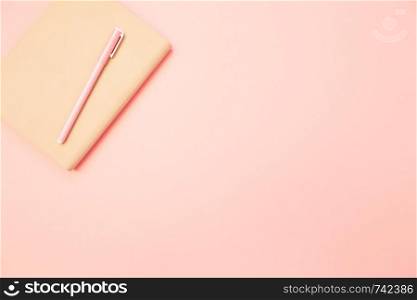 Beige diary with pink pen on pastel millennial pink paper background. Concept of education, blogging. Top view. Flat lay. Minimal style. Template for female blog. Lifestyle. Copy space.