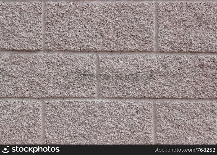 Beige-pink concrete background with a rectangular pattern imitating brickwork. Cladding material. Background or texture. For design or text.