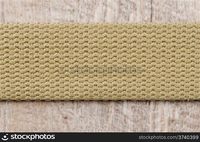 Beige textile belt over wooden background.
