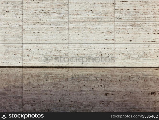 Beige textured travertine wall and reflection in a water. Barcelona Pavilion