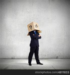 Being in confusion. Businessman wearing on head carton box with marks