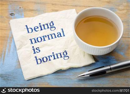Being normal is boring - handwriting on a napkin with a cup of tea