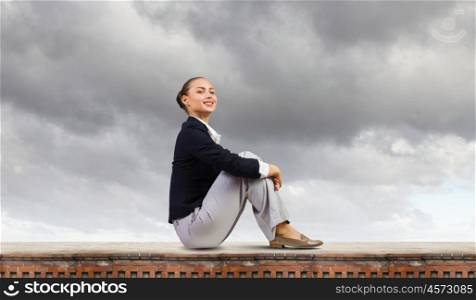 Being on top. Young attractive lady sitting on top of building