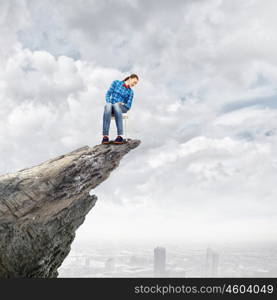 Being on top. Young woman in casual sitting in chair on top of rock