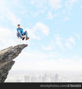 Being on top. Young woman in casual sitting in chair on top of rock