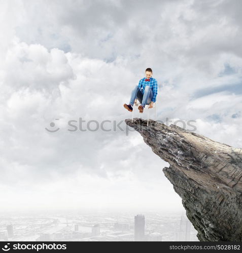 Being on top. Young woman in casual sitting in chair on top of rock