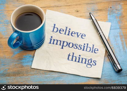 Beleive impossible things - inspirational handwriting on a napkin with a cup of espresso coffee